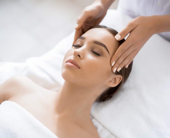Young woman enjoying spa procedure with her face in luxurious massage salon